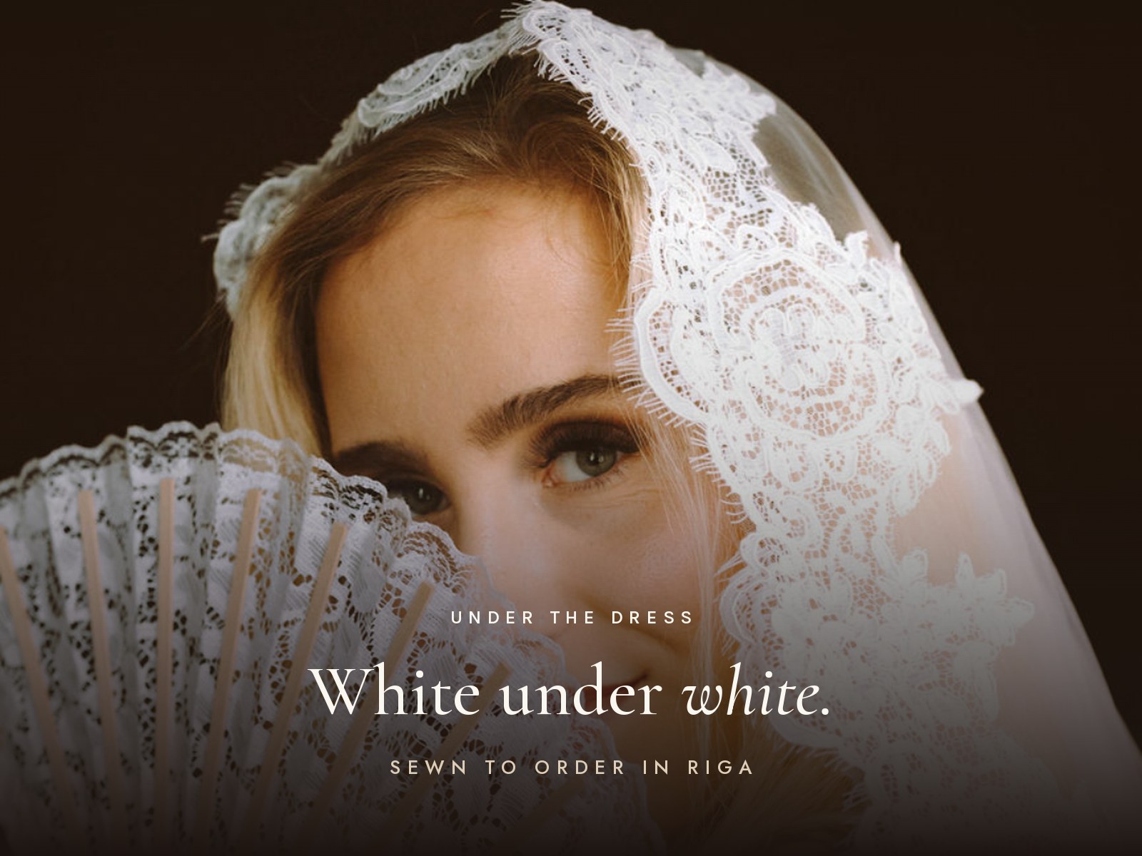 Bride behind a lace fan and veil — White under white